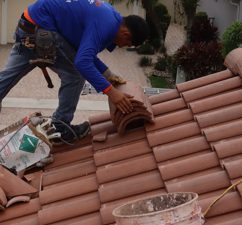A roofer securing terracotta roof tiles during a leak repair